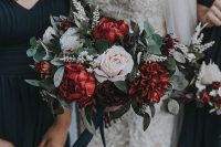 a bright Christmas wedding bouquet of burgundy and white blooms, greenery and white blooming branches