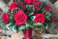 a bright Christmas wedding bouquet of red roses, berries and dried berries, pinecones and lots of greenery