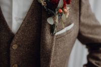 a brown tweed three-piece suit, a white button down, a burgundy velvet bow tie and a matching boutonniere