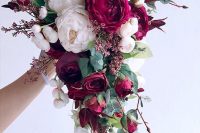 a cascading Christmas wedding bouquet of blush and burugundy blooms, greenery, bold leaves and herbs