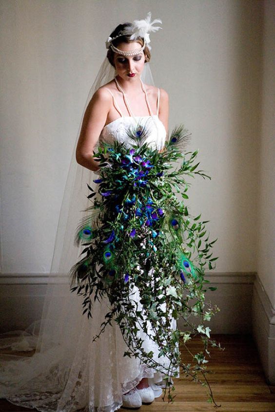 a cascading greenery wedding bouquet with purple orchids and peacock feathers will make a statement