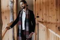 a casual and comfy winter groom’s look with a black velvet blazer, burgundy pants, a white button down and a bright scarf