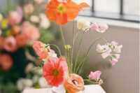 a catchy modern wedding centerpiece of coral, orange and light pink poppies, white and light pink blooms and greenery