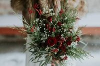 a catchy shaped Christmas wedding bouquet of burgundy blooms, baby’s breath and greenery