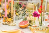 a colorful wedding tablescape with pink placemats, yellow napkins, hot pink blooms, yellow, pink and orange candles