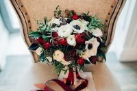 a contrasting Christmas wedding bouquet of red and white flowers, greenery, burgundy and white ribbons