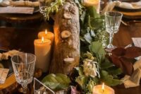 a cool fall woodland wedding reception table with a log candlelabra, candles, a clear table number and wood slice placemats