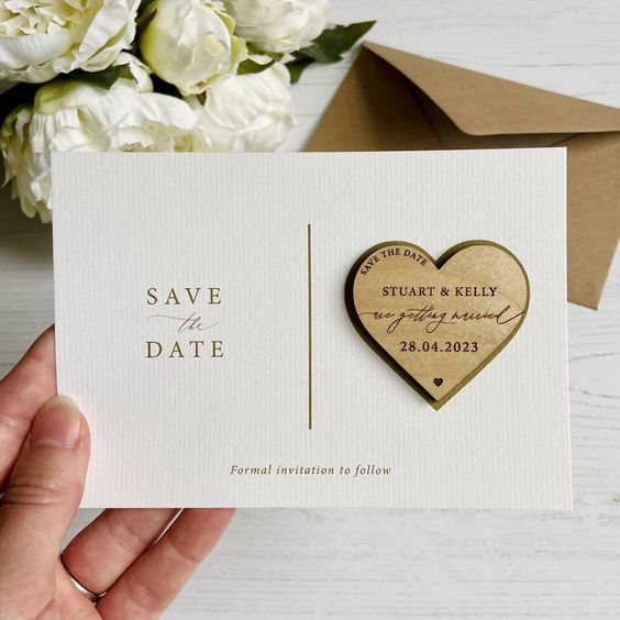 a cool save the date with a wooden heart magnet with wood burnt information is a lovely idea for a rustic wedding