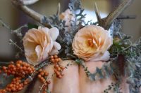 a fall wedding centerpiece a blush pumpkin, peachy blooms, pale greenery, berries and antlers on top is very cool
