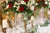 a festive Christmas wedding centerpiece of greenery, red and white blooms and a greenery runner and candles is chic and bold