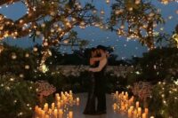 a gorgeous destination wedding ceremony space lit up with candleholders on the floor and hanging on the tree branches