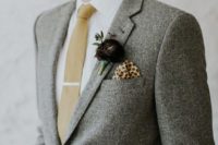 a grey twees suit, a white button down, a tan tie, a dark purple floral boutonniere for an elegant winter groom’s look