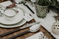 a hygge wedding table setting with a white knit table runner, simple porcelain, an evergreen table runner and berries