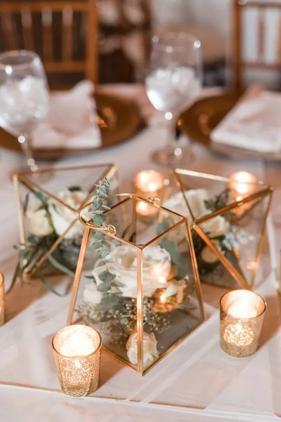 a lovely cluster of terrariums with white blooms and eucalyptus plus candles around is a very chic idea