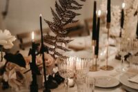 a lovely cluster wedding centerpiece of black candles, dried leaves and white roses is a very stylish idea to rock at a refined modern wedding