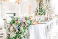 a lush floral table garland with greenery, lilac, pink, blue and yellow blooms going down to the floor