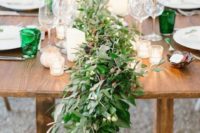 a lush greenery table garland with berries is a cool idea for a summer wedding