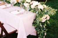 a lush greeneyr and white bloom table garland is a cool idea that substitutes any centerpieces easily