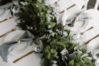 a lush woodland-inspired greenery table garland with various kinds of eucalyptus, moss and ferns