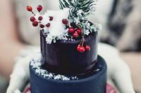 a mini Christmas wedding cake in navy and deep purple, topped with berries and evergreens to make a statement with color