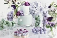a mint and purple wedding sweets bar with purple and mint floral arrangements and all kinds of delicious desserts