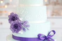 a mint wedding cake with white butterfly patterns, purple blooms and ribbon for a chic look