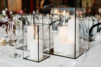a modern and classy wedding centerpiece of glass candle lanterns with pillar candles and some candles aorund is cool