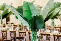 a modern centerpiece with large banana leaves and a clear vase – DIY it easily for your own wedding