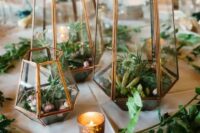 a modern cluster terrarium wedding centerpiece with thistles, succulents and rocks, with greenery and candles around is cool