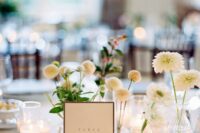 a modern cluster wedding centerpiece of clear vases and white dahlias and small candles is a lovely and fresh idea for a modern wedding