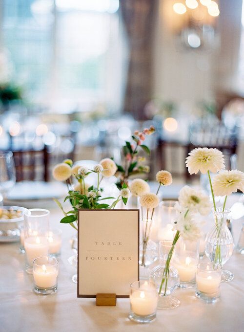 a modern cluster wedding centerpiece of clear vases and white dahlias and small candles is a lovely and fresh idea for a modern wedding