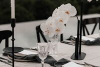 a modern refined wedding centerpiece of blakc tube vases with white orchids and white candles is a veyr stylish and chic solution