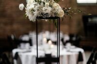 a modern tall wedding centerpiece on a black frame with white blooms and greenery is a stylish and chic idea for a modern wedding