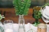 a modern urban jungle wedding centerpiece of a vase with fern leaves, succulents in a hexagon cover and candles is very cool