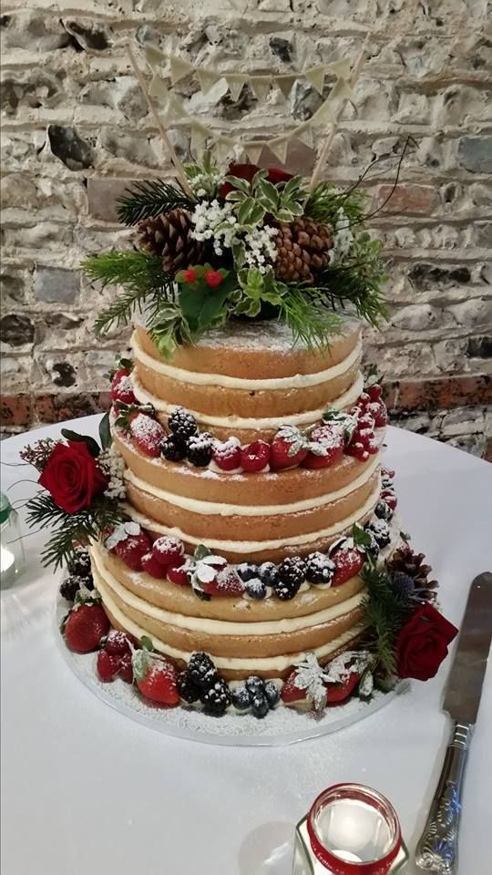 a naked Christmas wedding cake with sugared berries, greenery, pinecones and leaves is a bold and chic idea