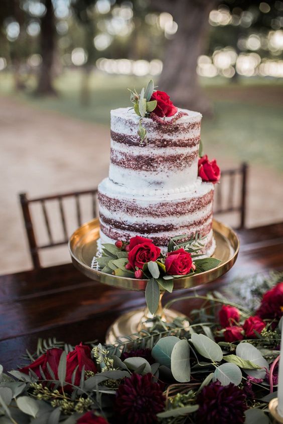 a naked chocolate wedding cake with greenery and red roses is a very Christmassy and cozy dessert to serve at your holiday wedding