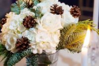 a natural Christmas wedding centerpiece of a glass vase, fir branches, white blooms and candles around is beautiful
