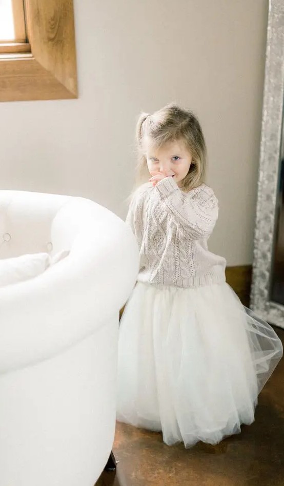 a neutral cable knit sweater and a white tutu skirt for a lovely and comfy winter flower girl look