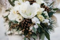 a neutral wedding bouquet of white blooms, pinecones, berries and greenery, gilded berries for Christmas