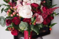 a pretty Christmas wedding bouquet of blush and burgundy blooms, berries and greenery plus a burgundy wrap