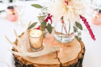 a pretty and bright wedding centerpiece of a wood slice, antlers, a candle and a neutral and pink bloom in a jar is easy to DIY