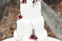 a pure white textural Christmas wedding cake with berries, white blooms and twigs is a bold and contrasting idea