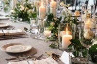 a refined Christmas wedding table setting with a greenery and white bloom runner, white candles, sivler cutlery and plates