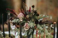 a refined moody secret garden wedding centerpiece of blush and dark blooms, greenery, berries and feathers is amazing for the fall