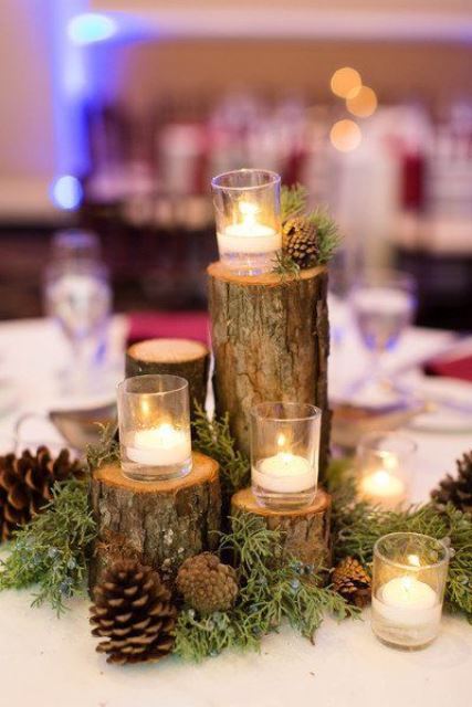 a rustic Christmas wedding centerpiece of wood stumps, candles and pinecones will fit a woodland wedding