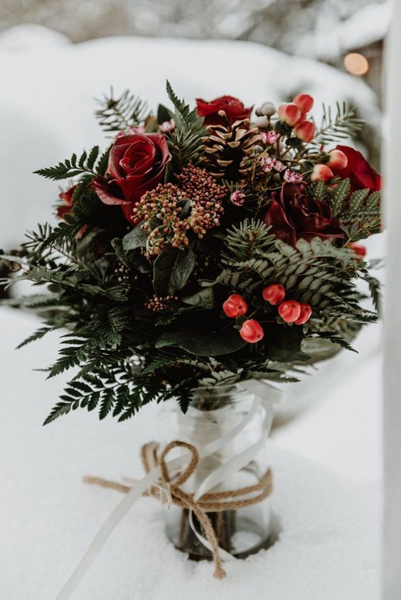 a rustic and bold Christmas wedding centerpiece of a jar with greenery, ferns, berries and red roses is amazing