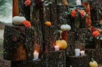 a rustic fall wedding altar made of tree stumps, candles, bold blooms, various mini pumpkins is a cool solution to rock