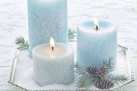 a silver tray with faux snow and silver and ice blue candles, pinecones and fir branches is a lovely centerpiece