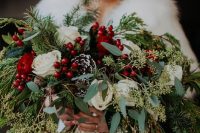 a spreading Christmas wedding bouquet of white blooms, berries, snowy pinecones, greenery and fir branches