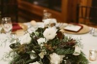 a stylish and non-typical Christmas wedding centerpiece of greenery ferns, white blooms and magnolia leaves is pure beauty